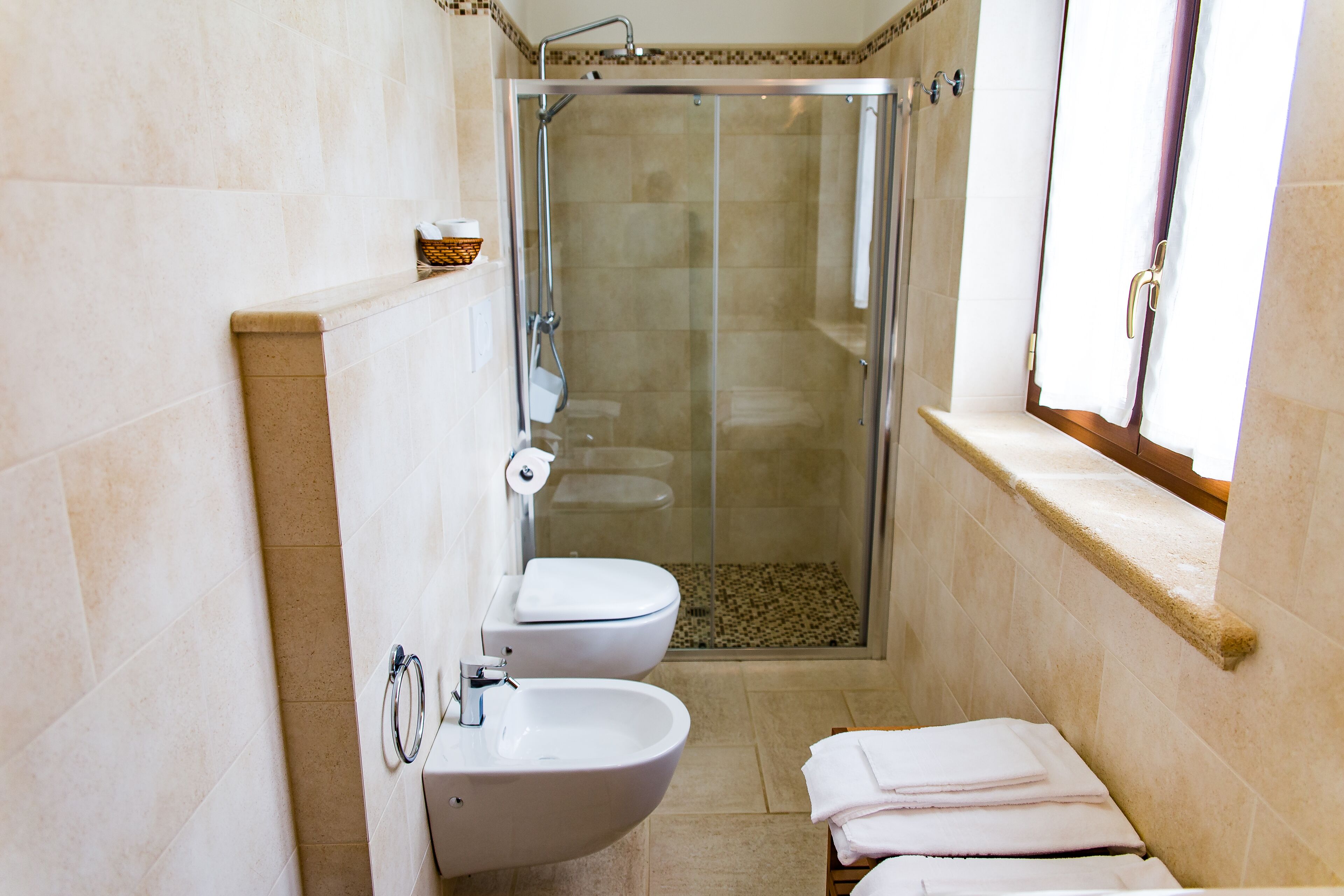 A bathroom with a glass-enclosed shower, a toilet, a sink, and a towel rack.