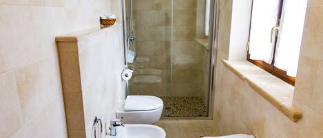 A bathroom with a glass-enclosed shower, a toilet, a sink, and a towel rack.