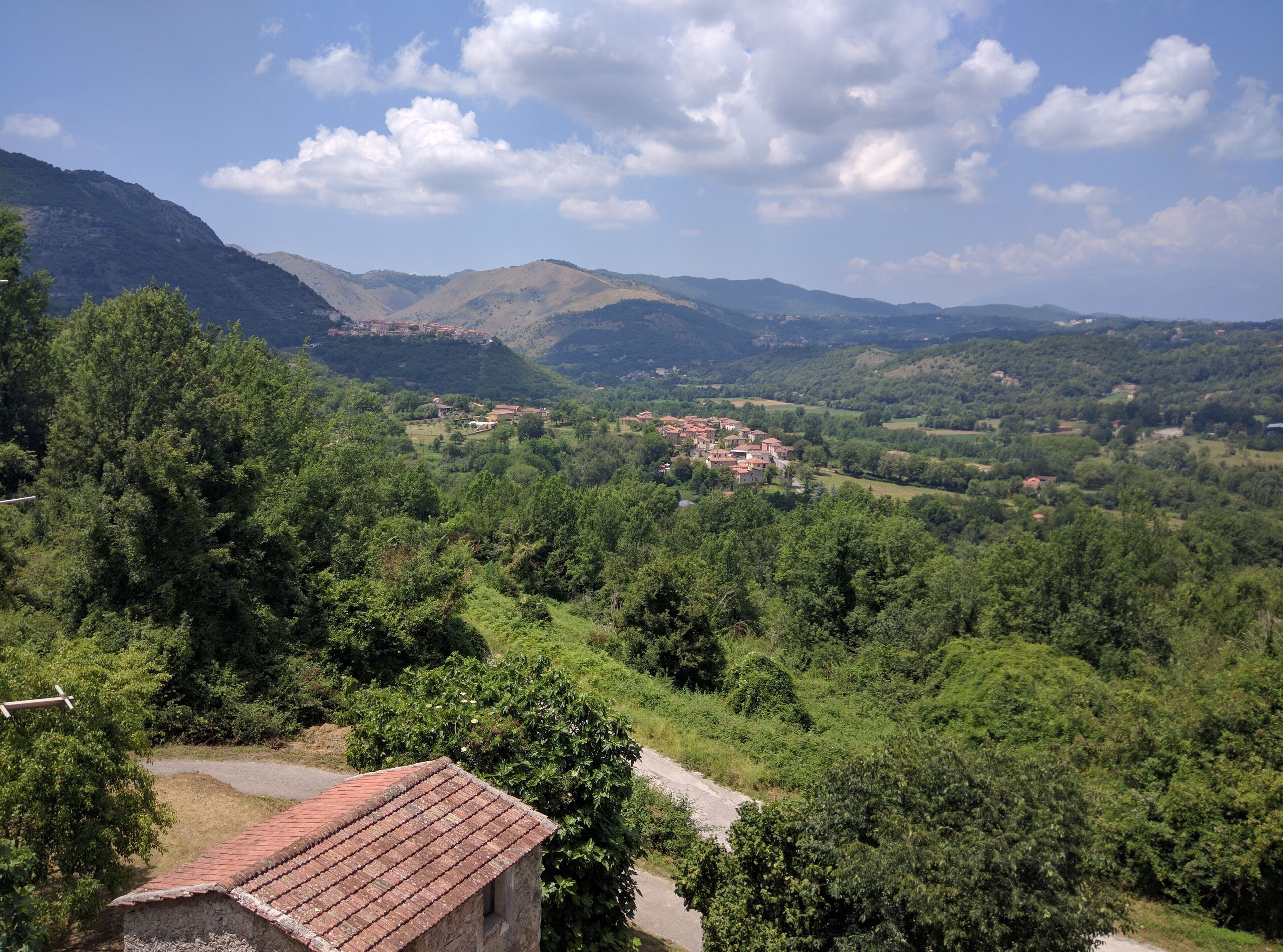 A rural landscape with a small village nestled among green hills and mountains.