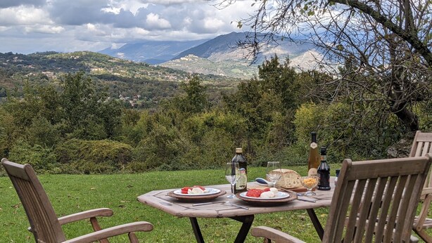 Une table de pique-nique installée sur une colline verdoyante, offrant une vue panoramique sur les montagnes.