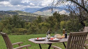 Una mesa de picnic sobre una colina cubierta de césped, con vistas a una montaña panorámica.