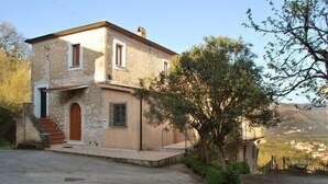 Une maison en pierre à deux étages, avec une porte en bois et un petit escalier menant à l’entrée.