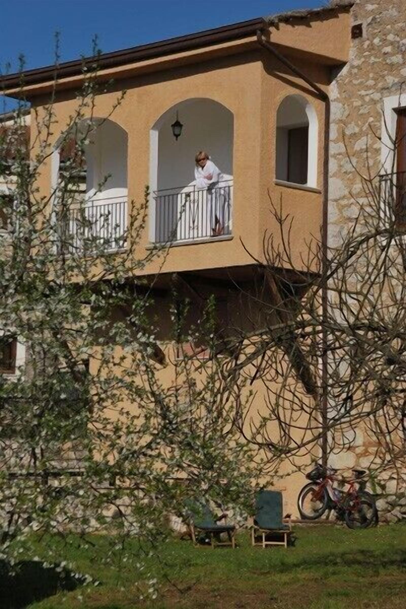 Un edificio con balcón, pared de piedra y una bicicleta.