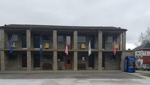 A two-story building with a stone facade, multiple windows, and flags. - The Guest House (Circleville)