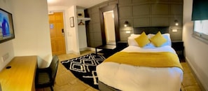 A hotel room with a bed, a desk, and a chair. There is a door leading to another room. - Siberia Bar & Hotel (Aberdeen)