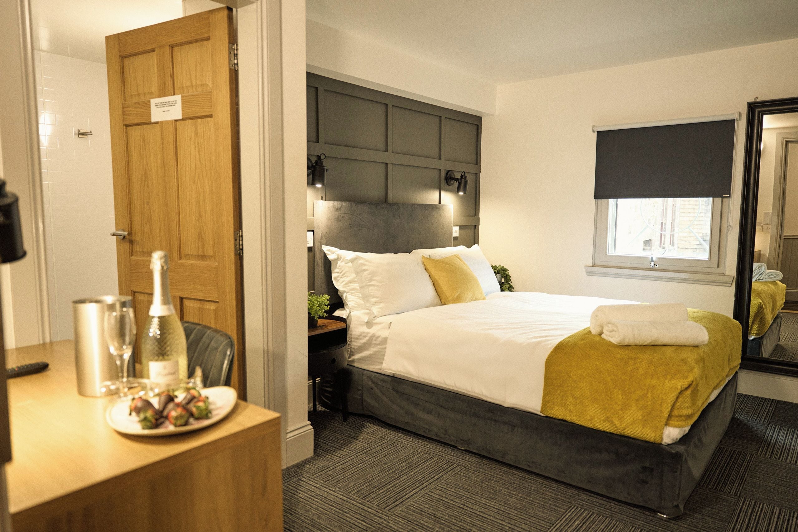 Una habitación de hotel con cama, mesita de noche y espejo.