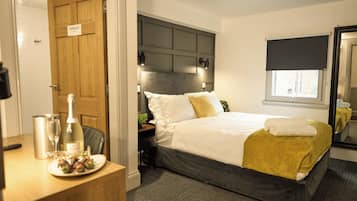 A hotel room with a bed, bedside table, and a mirror.