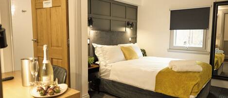 A hotel room with a bed, bedside table, and a mirror.