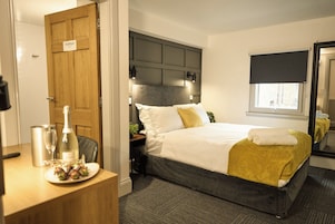 A hotel room with a bed, bedside table, and a mirror.