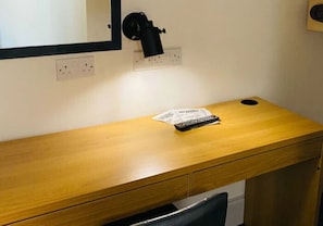 A wooden desk with a remote control and a piece of paper on it.