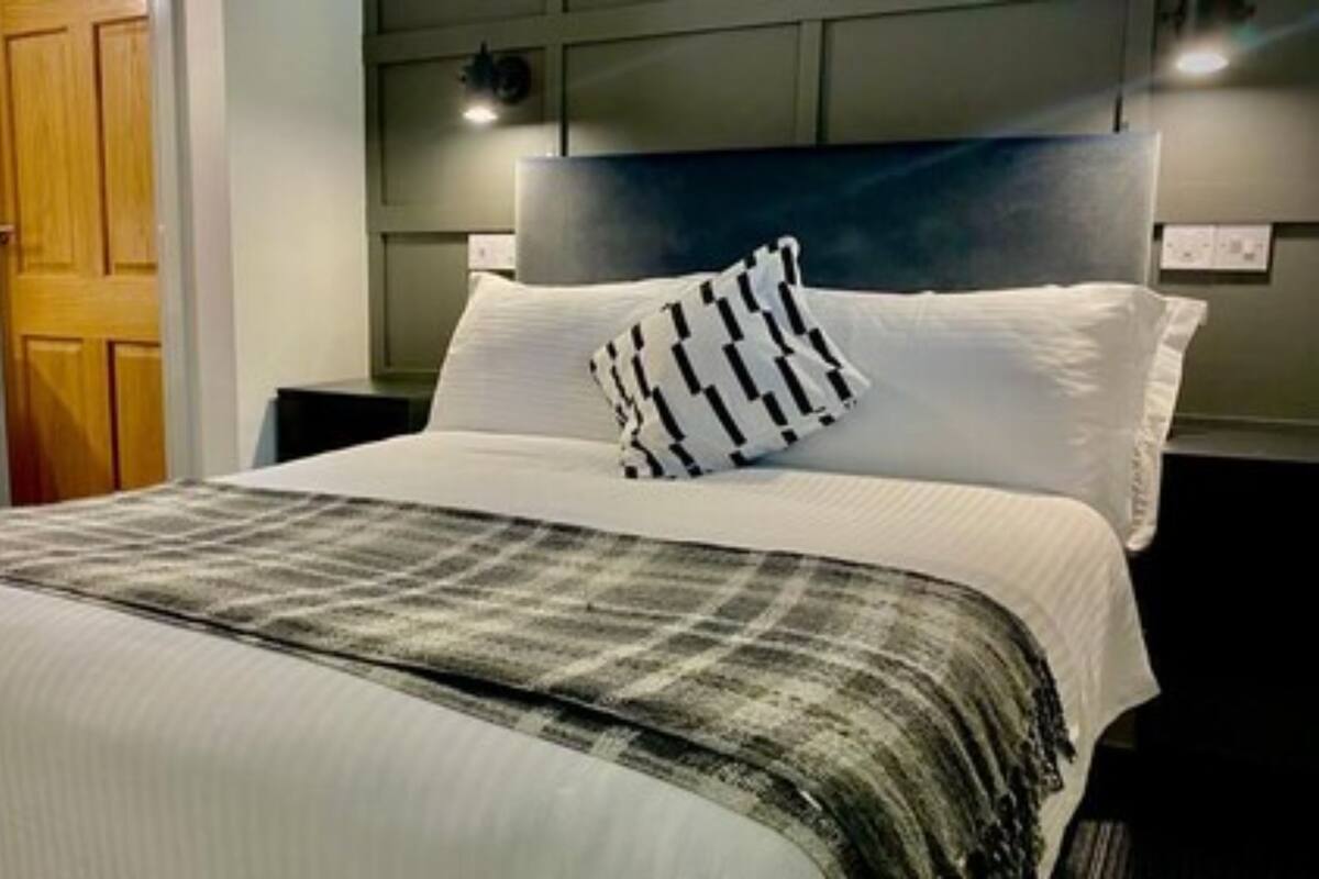 A hotel room with a large bed, a headboard, a desk, and a chair.