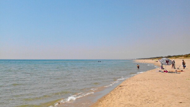 A beach with clear skies, calm water, and a few people. - Holiday in a comfortable and renovated ancient villa (mottola)