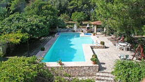 A rectangular swimming pool surrounded by stone walls and potted plants, with outdoor seating and a pergola in the background. - Holiday in a comfortable and renovated ancient villa (mottola)