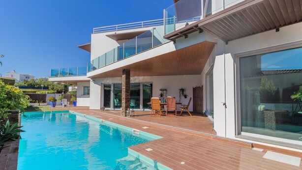 A modern house with a swimming pool, wooden deck, and outdoor seating area. - Cascade House,  Luxury Vila in Carvoeiro (Carvoeiro)