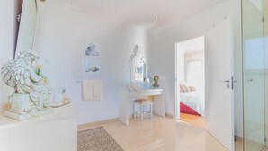 A modern bedroom with a glass door leading to a balcony, a white desk with a mirror, and a bed with red bedding. - Cascade House,  Luxury Vila in Carvoeiro (Carvoeiro)