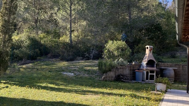A backyard with a brick barbecue area, a stone wall, and a grassy lawn. - Villetta dei lecci - Charming detached cottage (Monteverdi Marittimo)