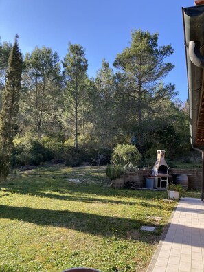 A backyard with a brick barbecue area, a stone wall, and a grassy lawn. - Villetta dei lecci - Charming detached cottage (Monteverdi Marittimo)
