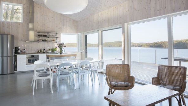 Una cocina moderna con armarios blancos, un refrigerador de acero inoxidable y un amplio ventanal con vista a un lago.