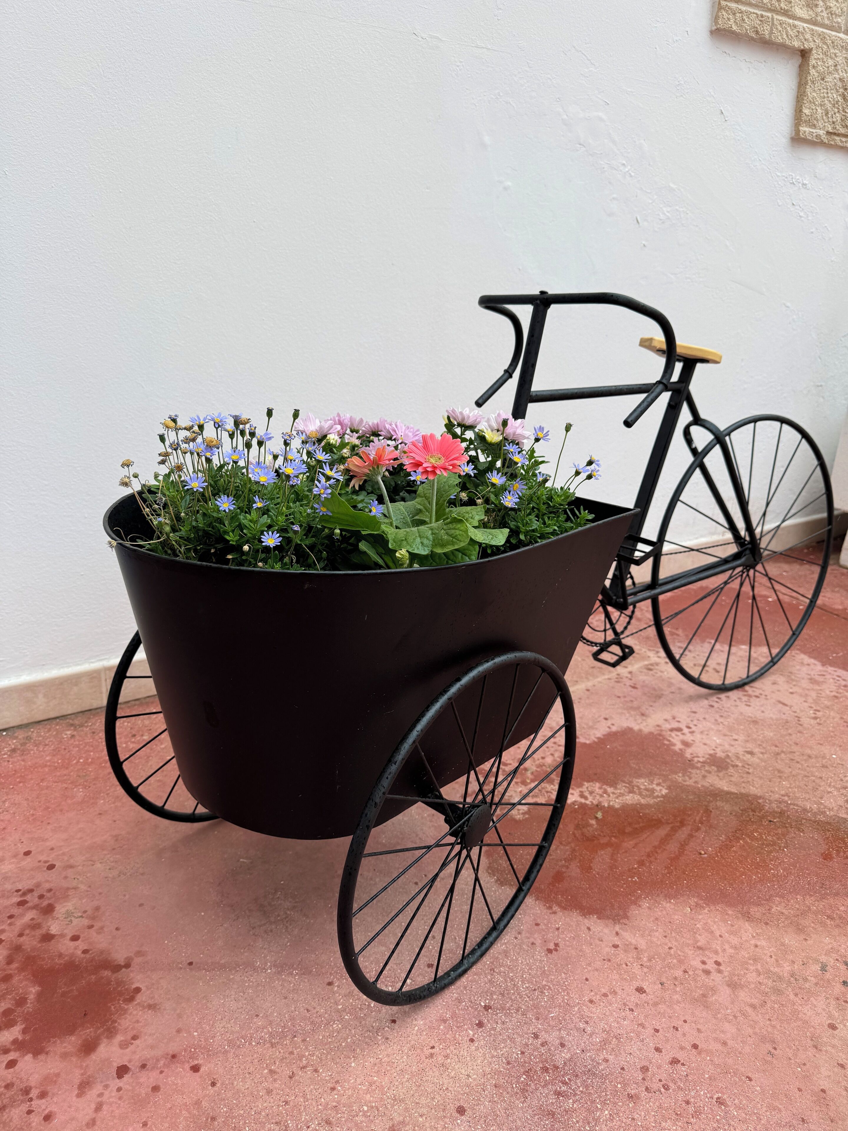 Un carretón negro con flores y una bicicleta.