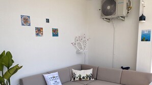 A living room with a beige sofa, a white coffee table, and a potted plant. - B&B Santa Maria di Leuca (Castrignano del Capo)
