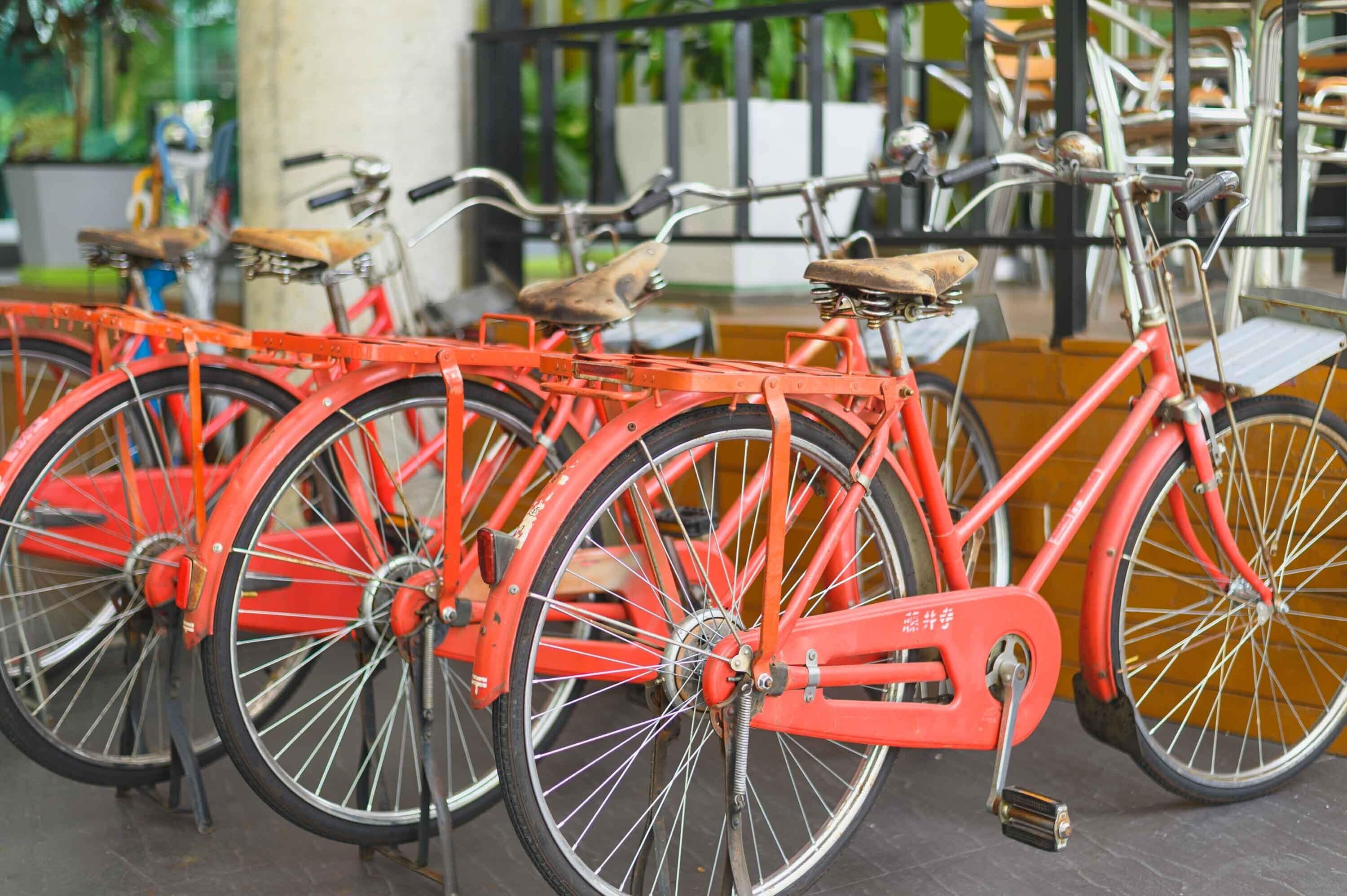 Uma fileira de bicicletas vermelhas estacionadas em um espaço interno com grades de metal e piso de concreto.
