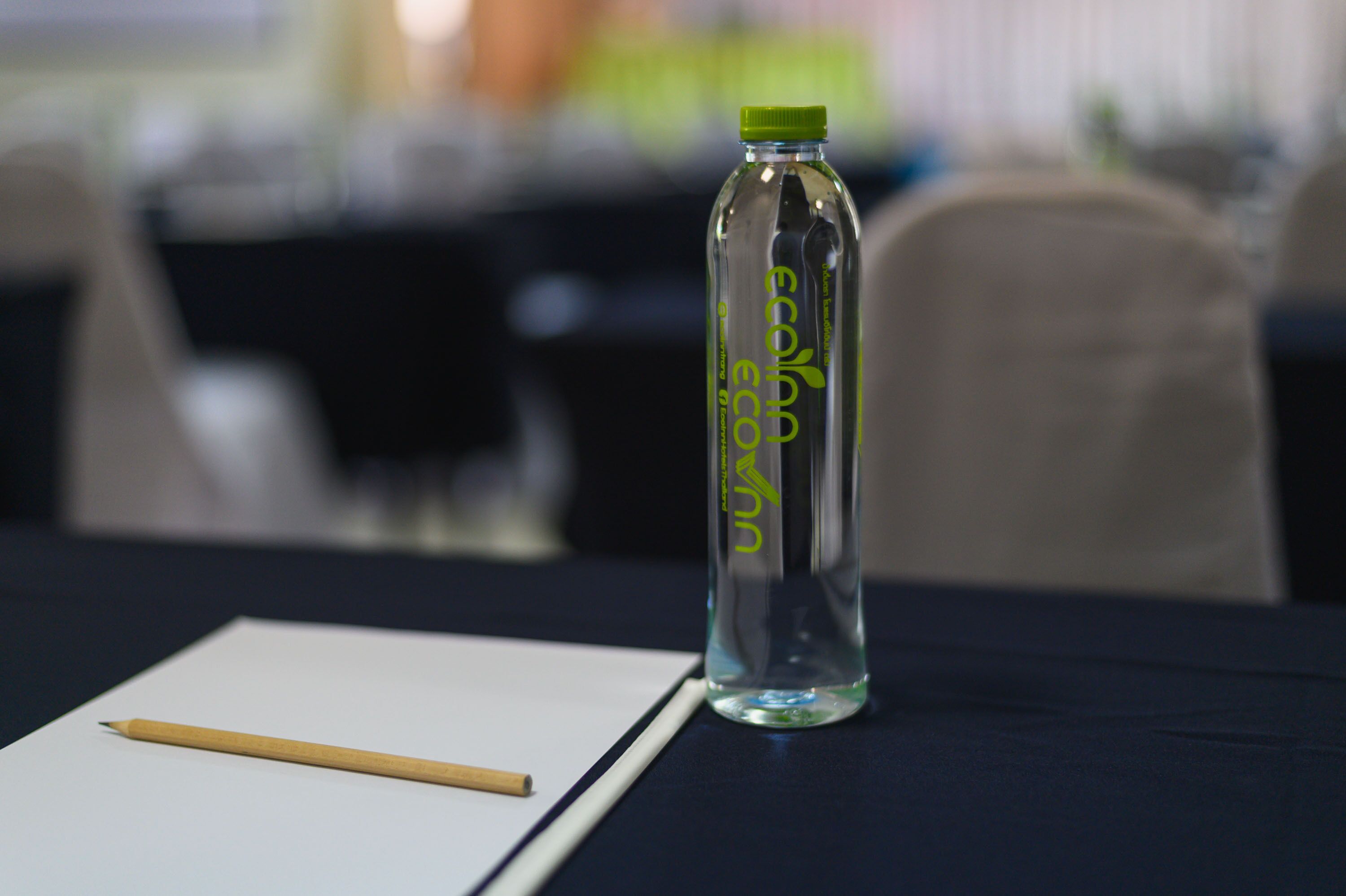 A clear glass bottle with a green cap and the text "eco" on a table.
