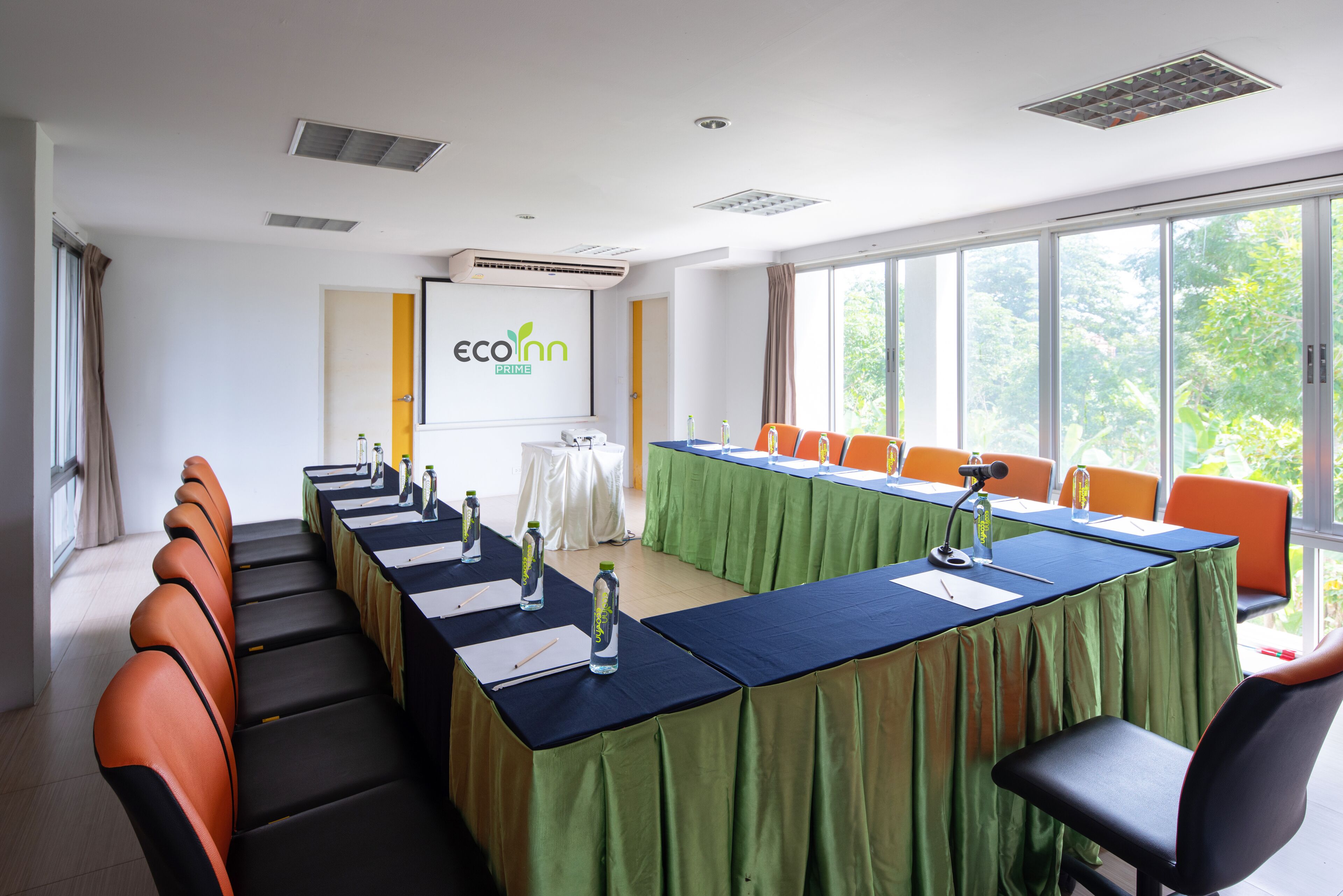 A conference room with a long table, chairs, and a projector screen.