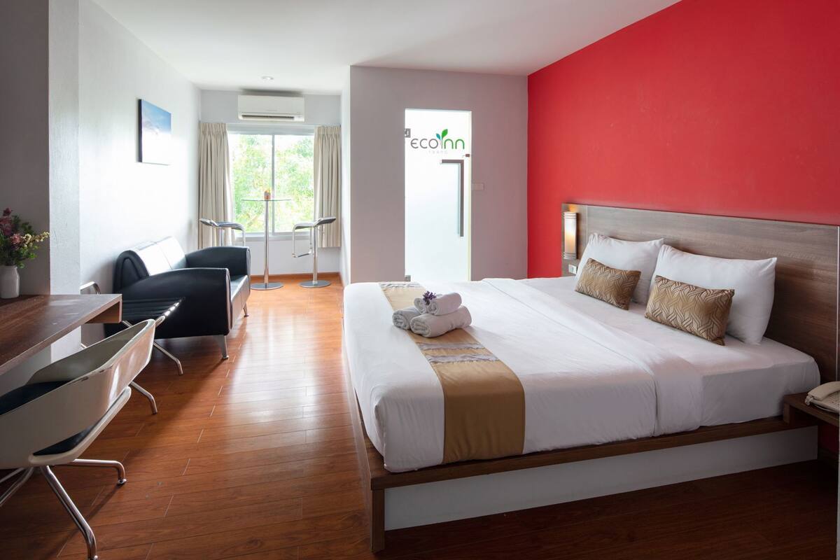 A hotel room with a bed, a desk, a chair, and a view of the outdoors.