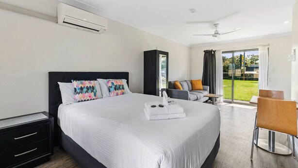 A modern hotel room with a large bed, a desk, and a view of the outdoors. - Lemon Tree Passage Motel (Lemon Tree Passage)