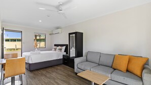 A modern hotel room with a bed, sofa, and a dining area. - Lemon Tree Passage Motel (Lemon Tree Passage)