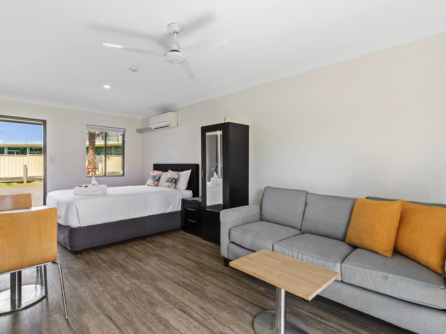 Una habitación de hotel moderna con cama, sofá y zona de comedor.