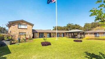 A building with a flagpole, a lawn, and a small garden area.
