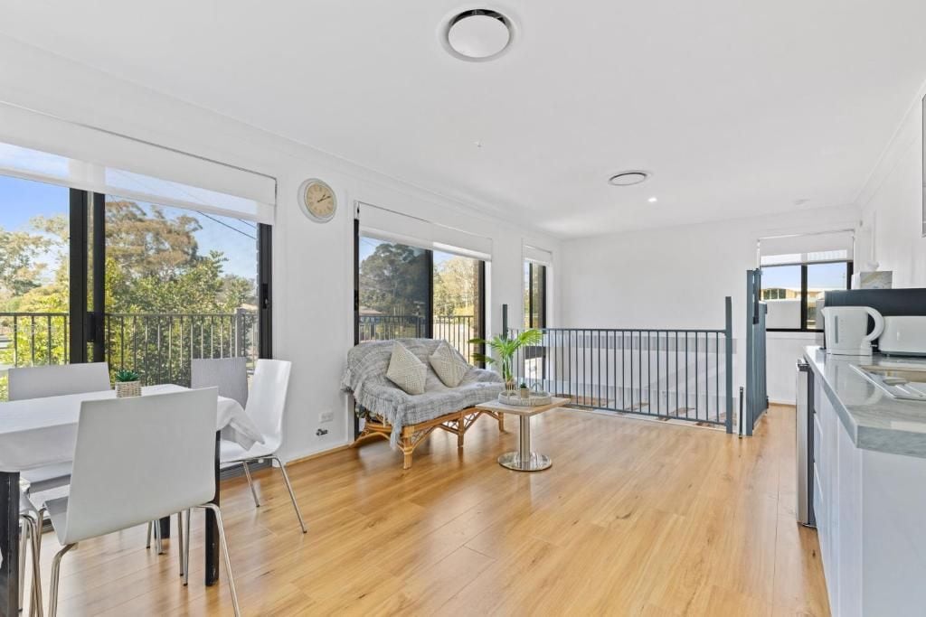 A spacious living area with a dining table, a sofa, and a balcony with a railing.