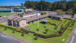 A hotel with multiple buildings, a parking lot, and a well-maintained lawn area. - Lemon Tree Passage Motel (Lemon Tree Passage)