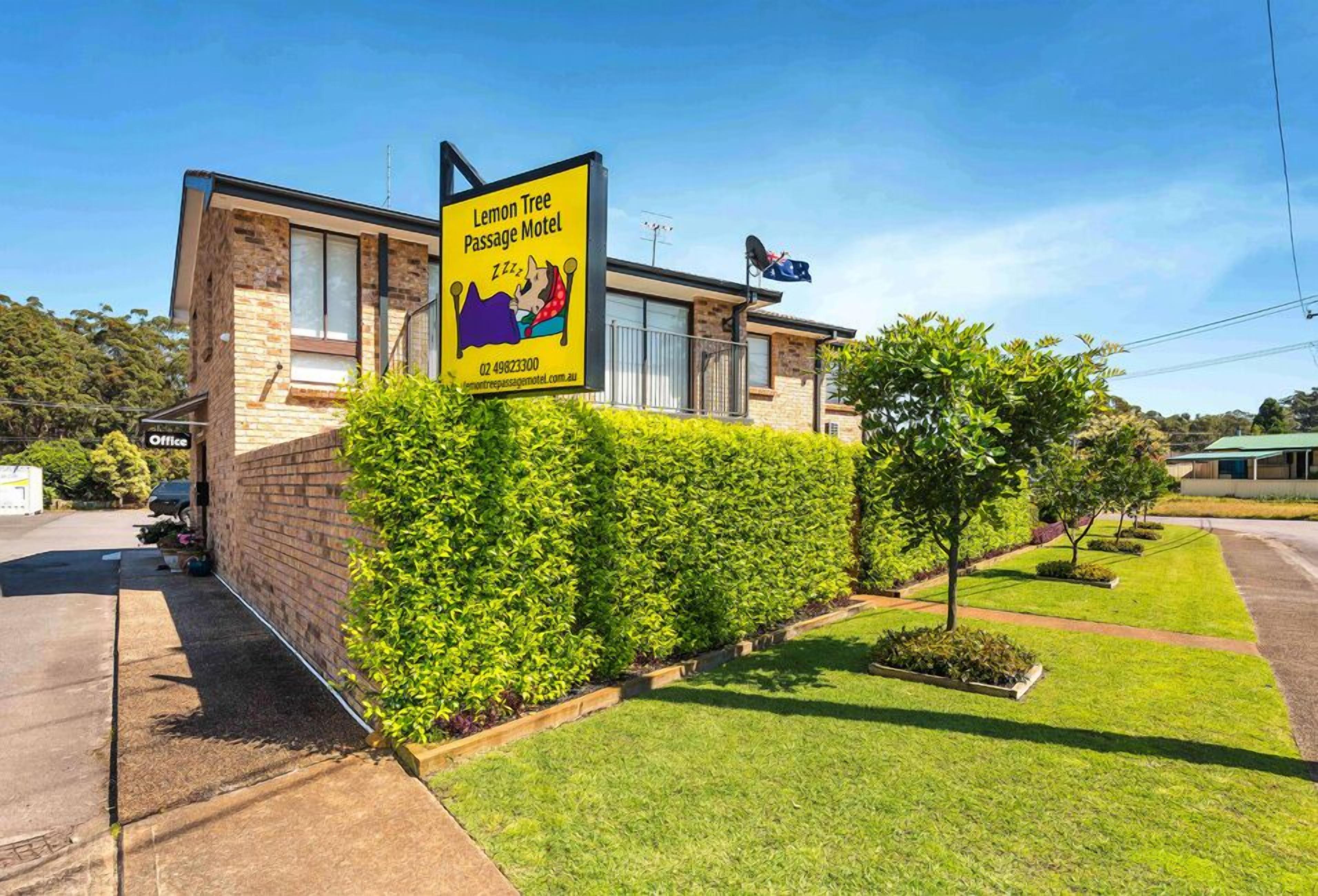 A building with a sign for Lemon Tree Passage Motel, featuring a large window and a brick facade.