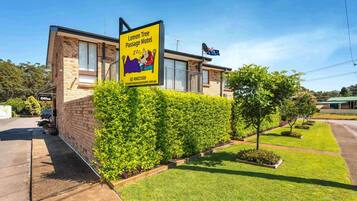 A building with a sign for Lemon Tree Passage Motel, featuring a large window and a brick facade.