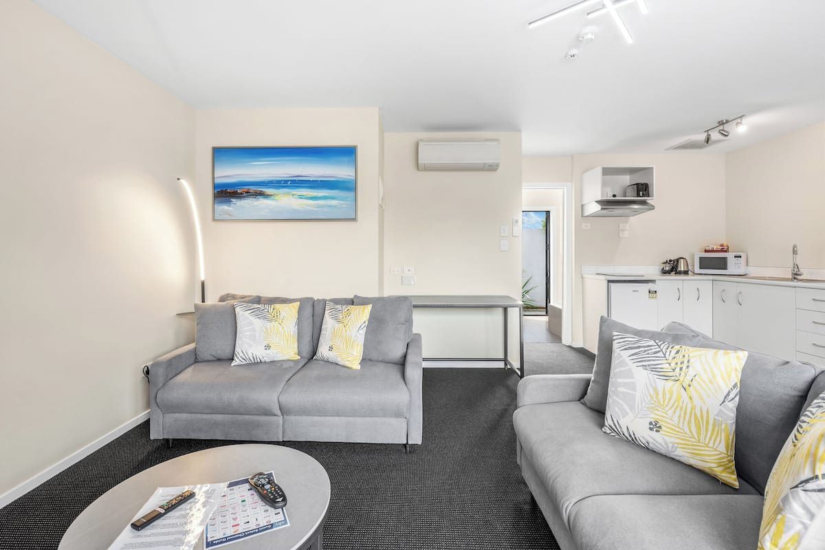 A modern living room with a grey sofa, a coffee table, and a painting of a beach scene.
