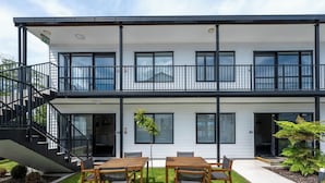 A two-story building with a balcony, outdoor seating area, and a staircase. - ASURE Rotorua International Motor Inn (Rotorua)