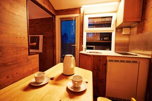 Una cucina compatta con mobili in legno, una finestra con persiane, un lavello e un bollitore sul piano di lavoro.