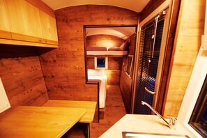 Una cabina angusta con un letto a castello, un tavolino e un lavandino.