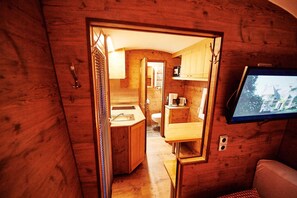 Un ambiente interno compatto con angolo cottura, bagno piccolo e televisore a parete.