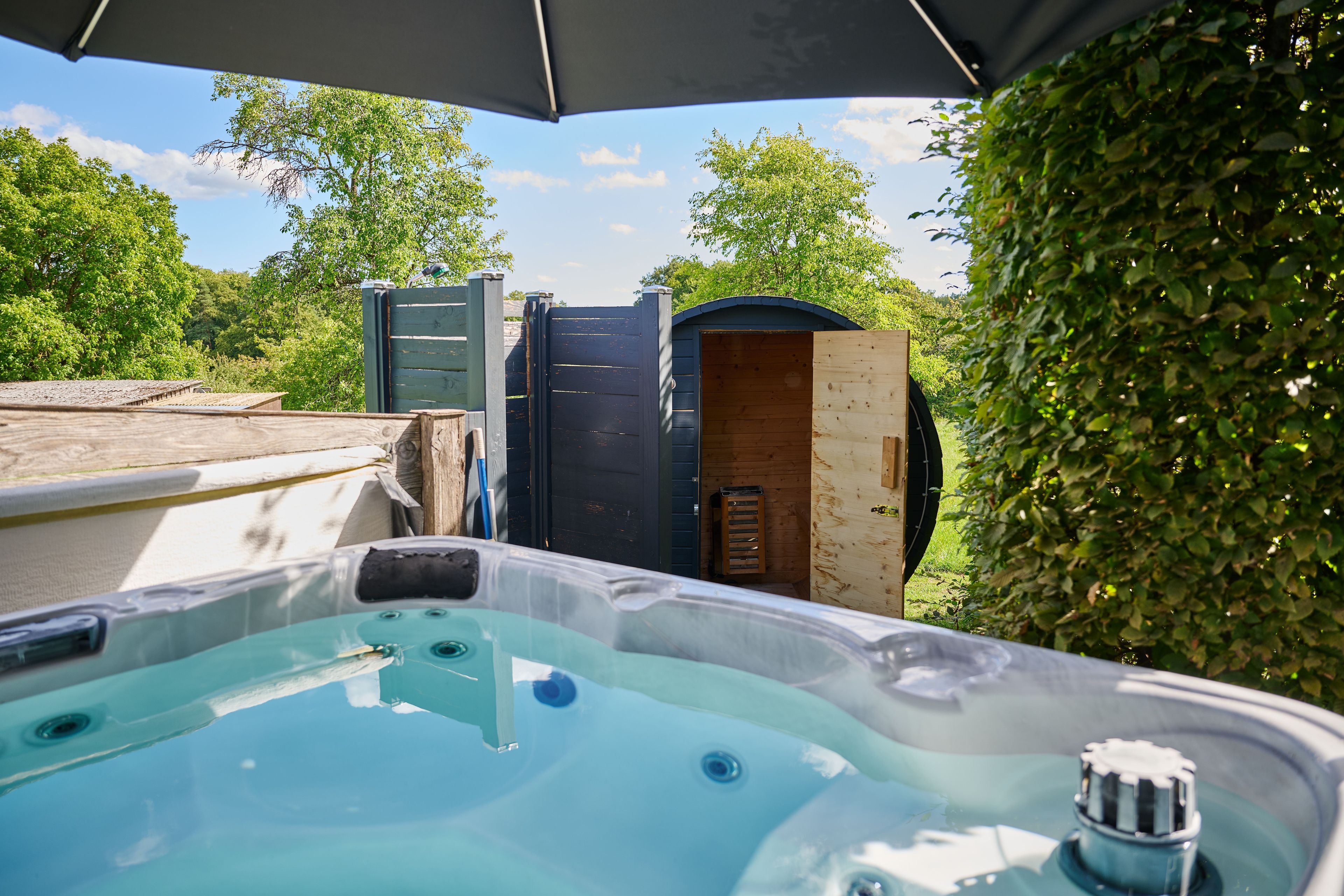 A hot tub with a wooden deck and a wooden structure in the background.