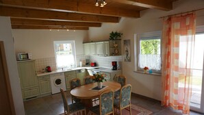 Una cocina con mesa, sillas, lavadora y ventana con cortinas.