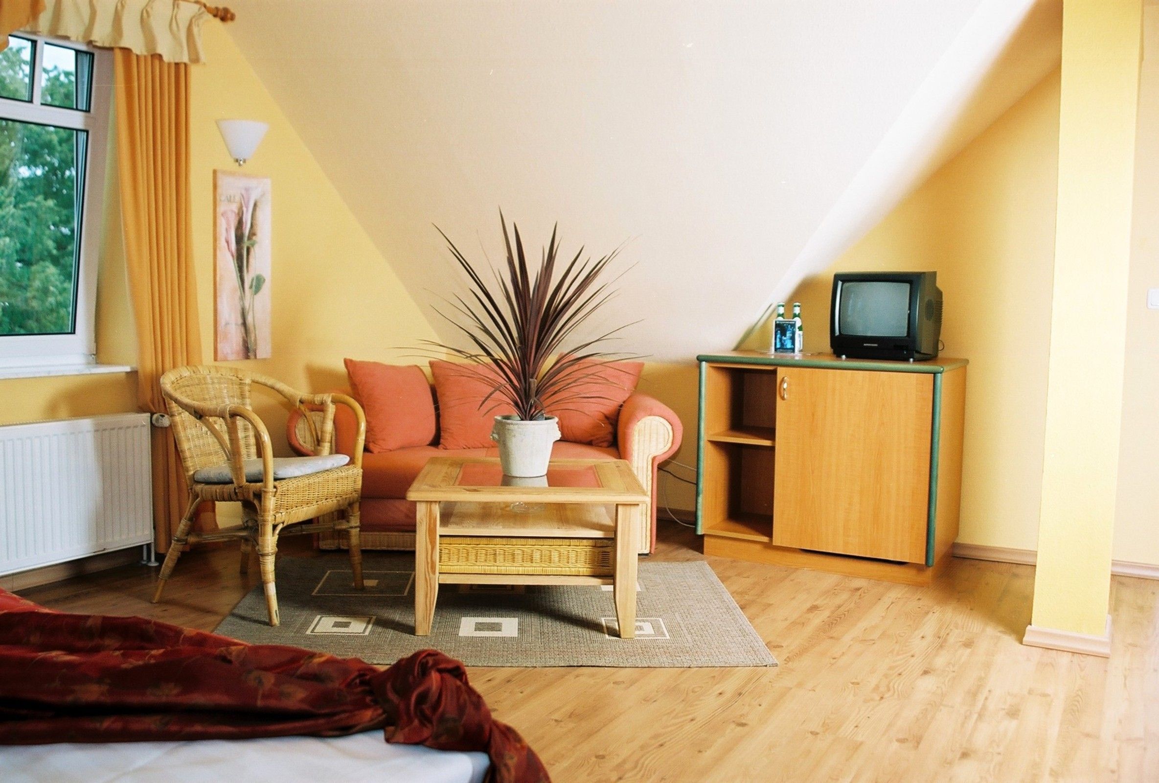 A cozy living room with a sofa, two chairs, a coffee table, a television on a cabinet, and a window with curtains.