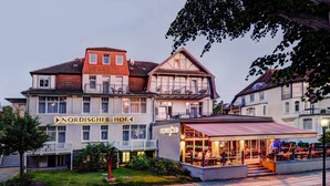 Hotel com restaurante no andar térreo, varanda e placa com a inscrição 'NORDISCHER HOF'.