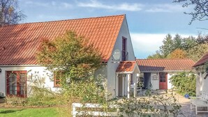 Ein zweistöckiges Haus mit rotem Ziegeldach, einer Satellitenschüssel und einem kleinen Garten mit weißem Zaun.