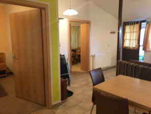 A dining area with a table and chairs, a radiator, and a door leading to another room. - FH 2B - house B (Dobbertin)