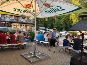 An outdoor dining area with tables and umbrellas, a grill, and a building with a sign that reads "Insel-Hotel." - FH 2B - house B (Dobbertin)