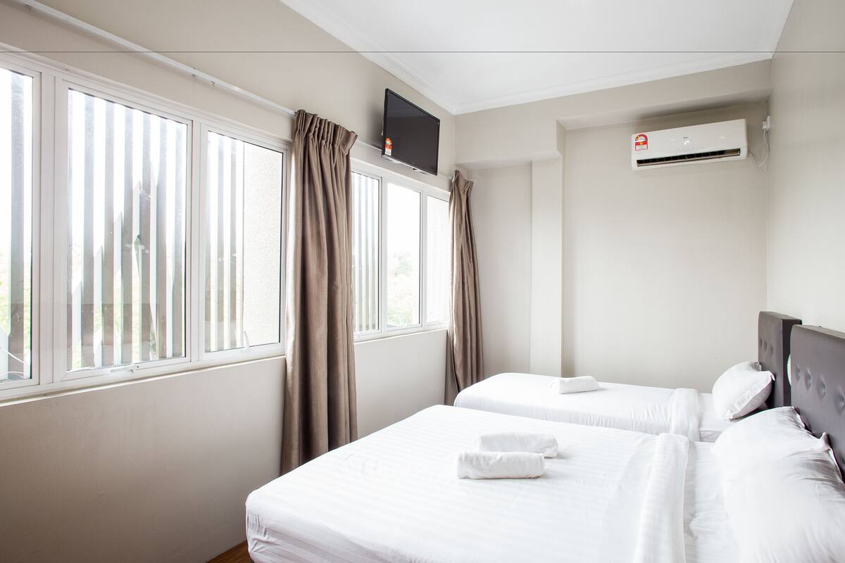 Ein Hotelzimmer mit zwei Betten, einem Wand-Fernseher und einer Klimaanlage.