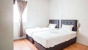 A double bed with a dark headboard, a bedside table, and a wall-mounted phone. - Moment Hotel (Petaling Jaya)